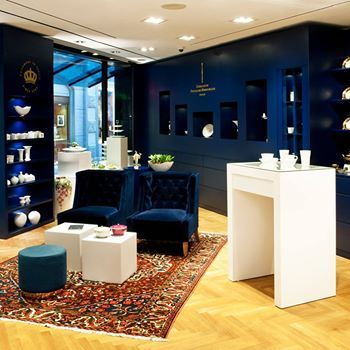 Store-Lounge mit tiefblauer Wandgestaltung und eleganten Sitzmöbeln