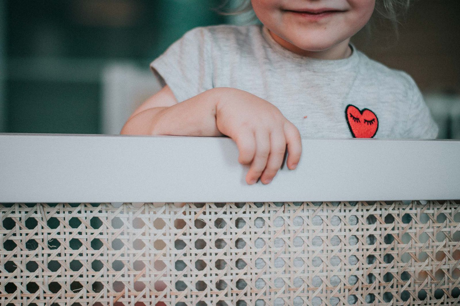 Kind greift durch das Wiener Geflecht des Bettes, Detailaufnahme der Struktur